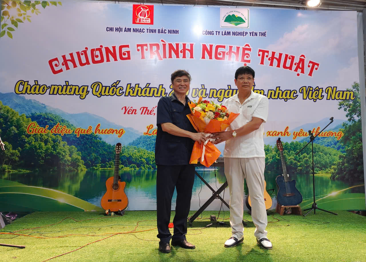 Nhạc sĩ Nguyễn Trung đại diện Chi hội Âm nhạc nhận hoa chúc mừng của ông Hoàng Văn Chúc - Chủ tịch HĐ Công ty Lâm nghiệp Yên Thế